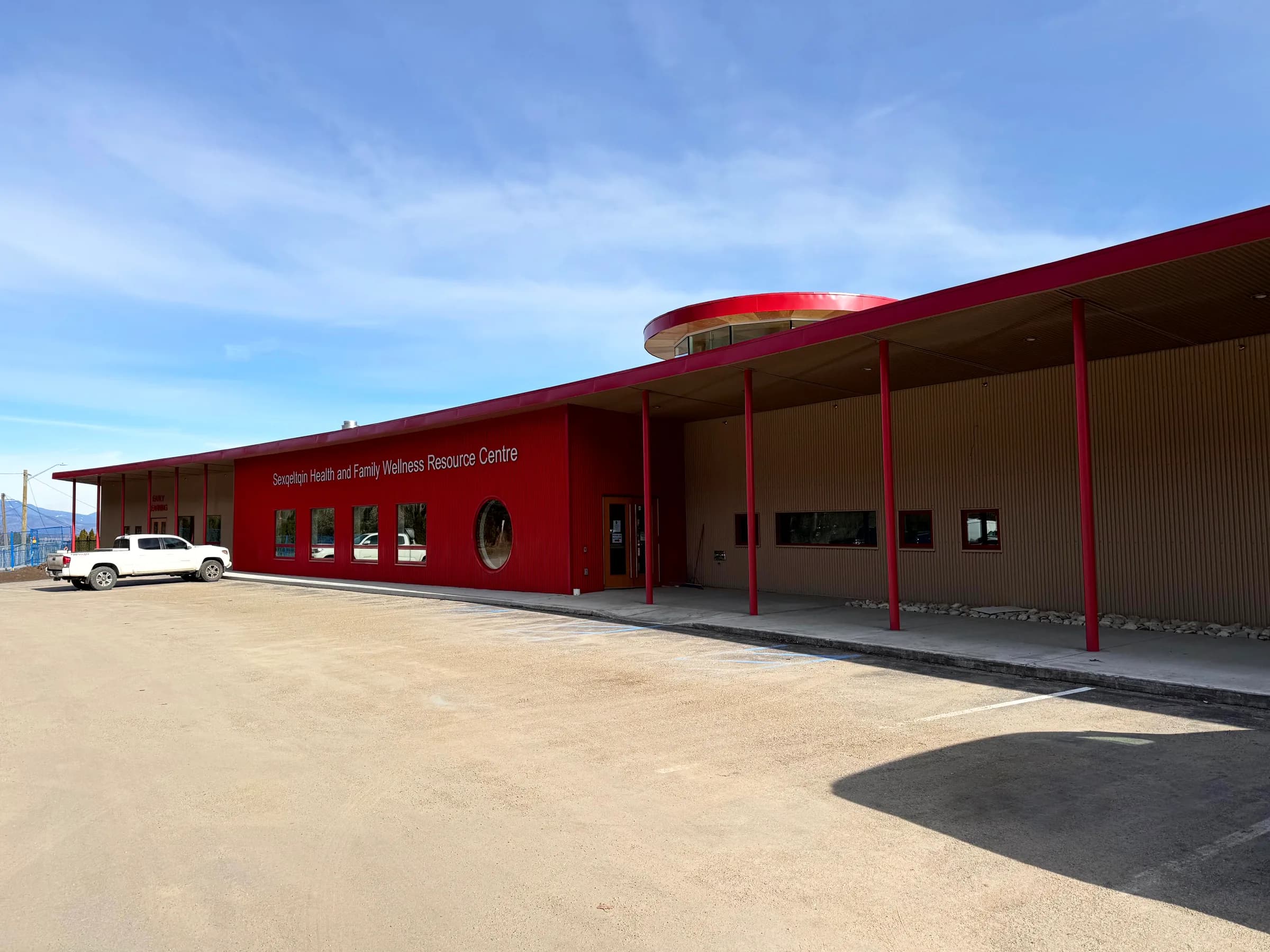 Centre achevé, façade et fines colonnes rouges près du stationnement sous les collines.