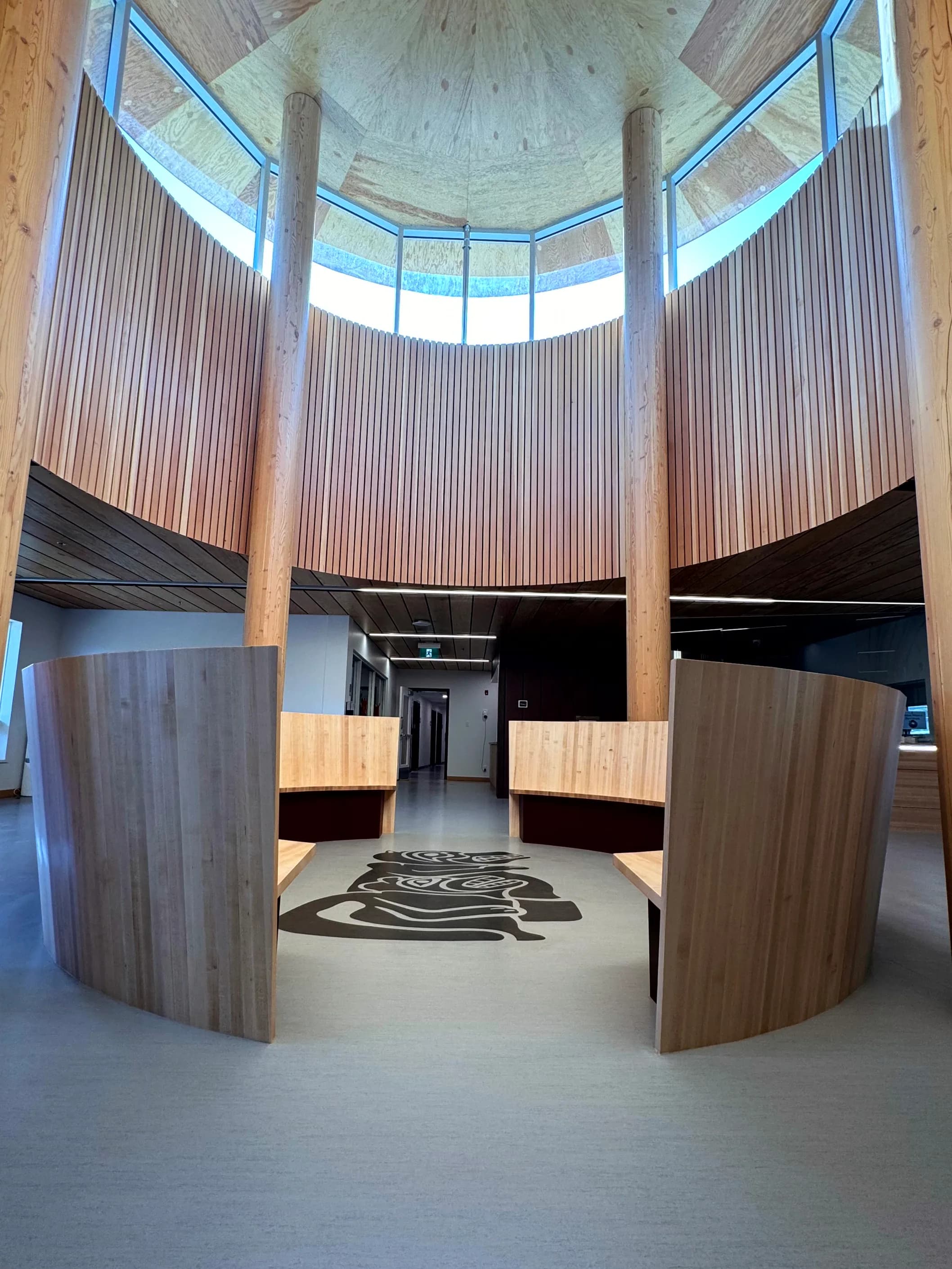 Espacio circular con madera vertical y gráfico central en suelo.