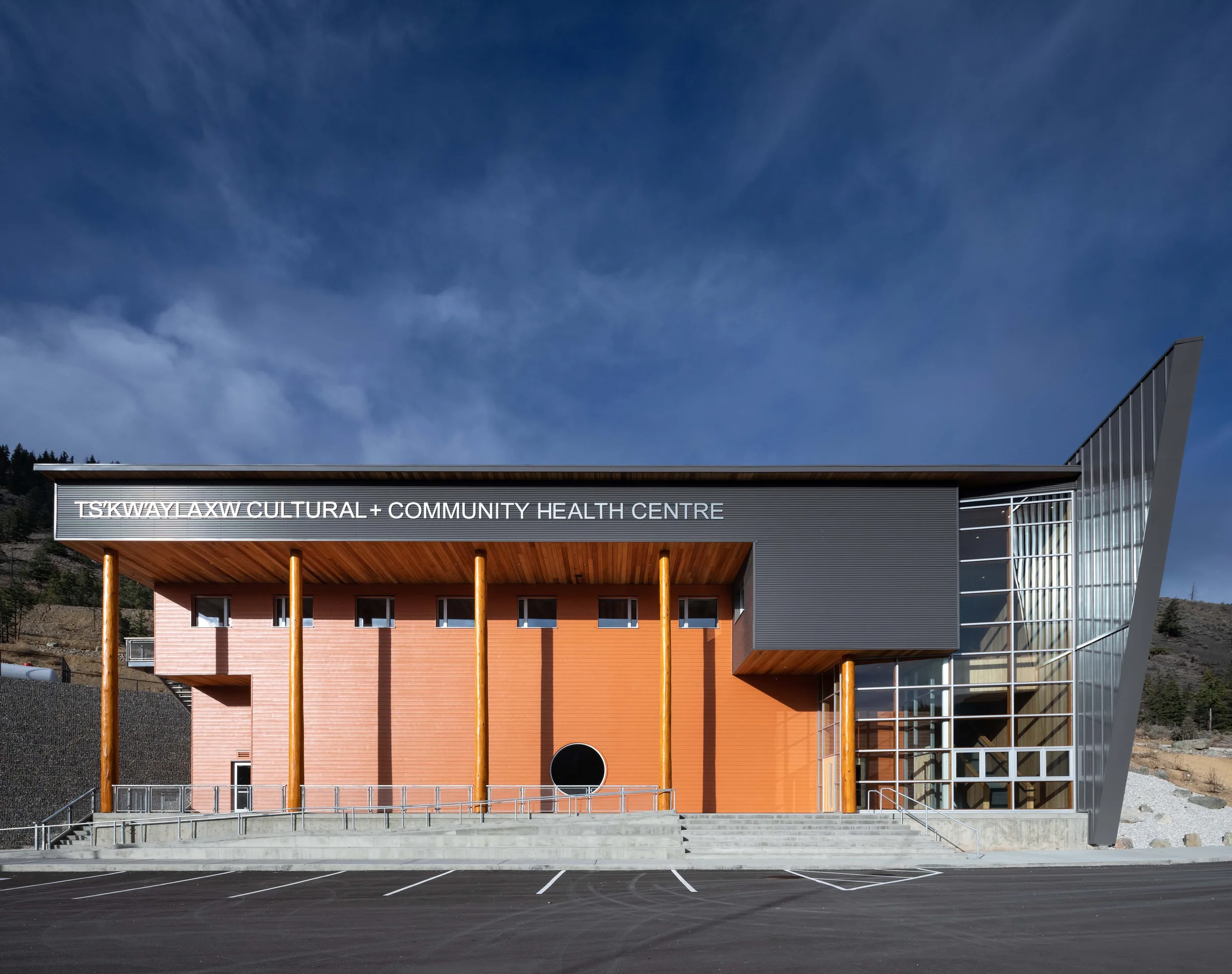 The completed centre at dusk, its facade and angled metal roof set against the dry hills of the Pavilion Mountain.