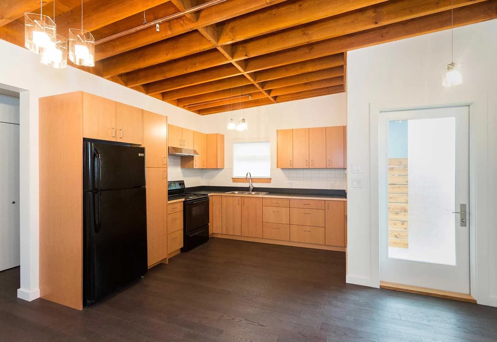Interior photo showing combination of exposed wood panels for ceiling and modern kitchen